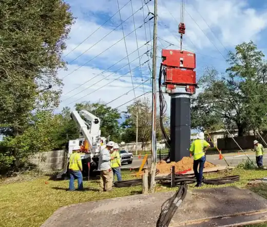 Crew and crane positioning foundation equipment beside utility lines