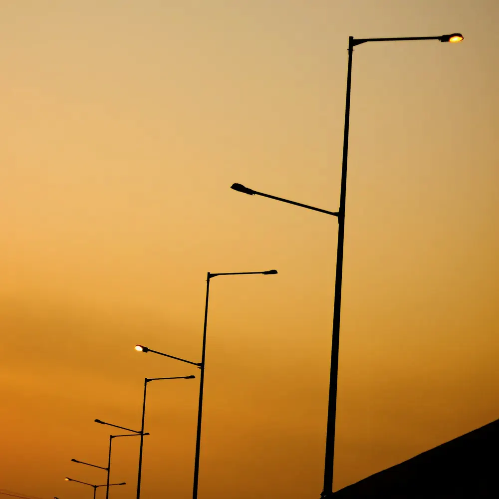 Streetlight poles against an evening sky