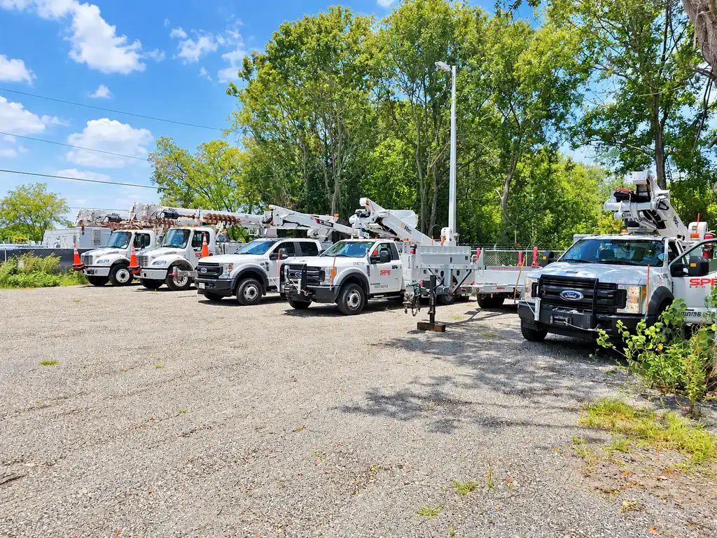 SPE bucket trucks lined up in a gravel fleet yard